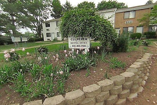 a sign in a garden in front of a house