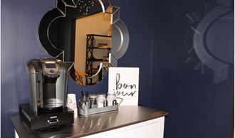 a coffee maker on a counter with a mirror and a coffee pot on a table