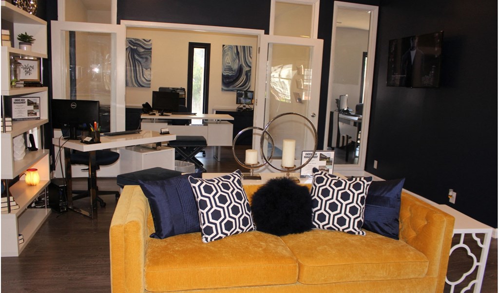 a living room with a yellow couch and black and white pillows