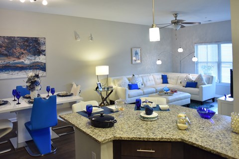 a living room and dining room with couches and a table with blue chairs
