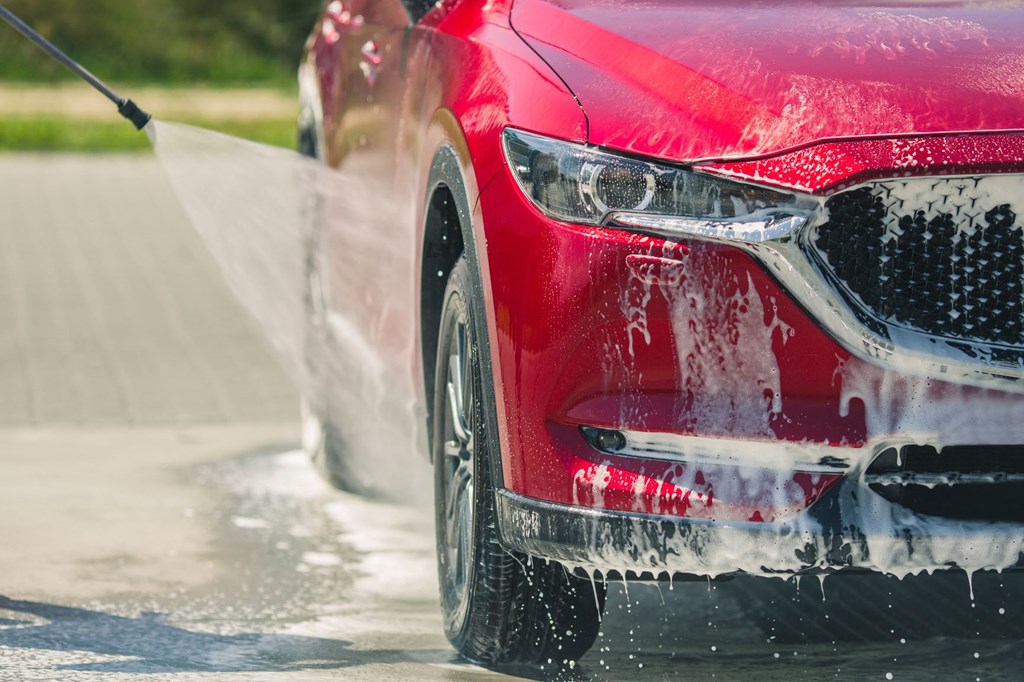 a red car getting sprayed with water from a hose