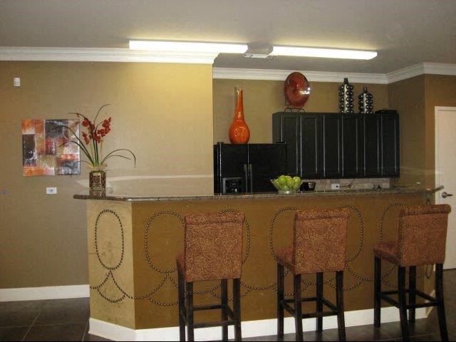 a kitchen with a bar and three chairs