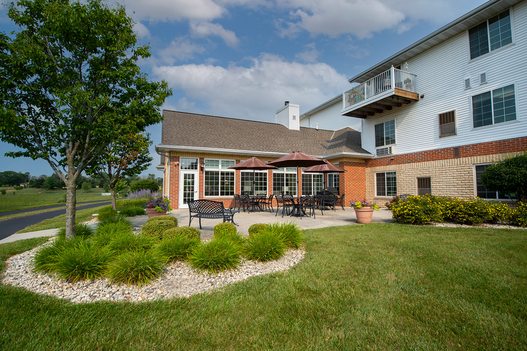 a patio with tables and umbrellas in front of a house