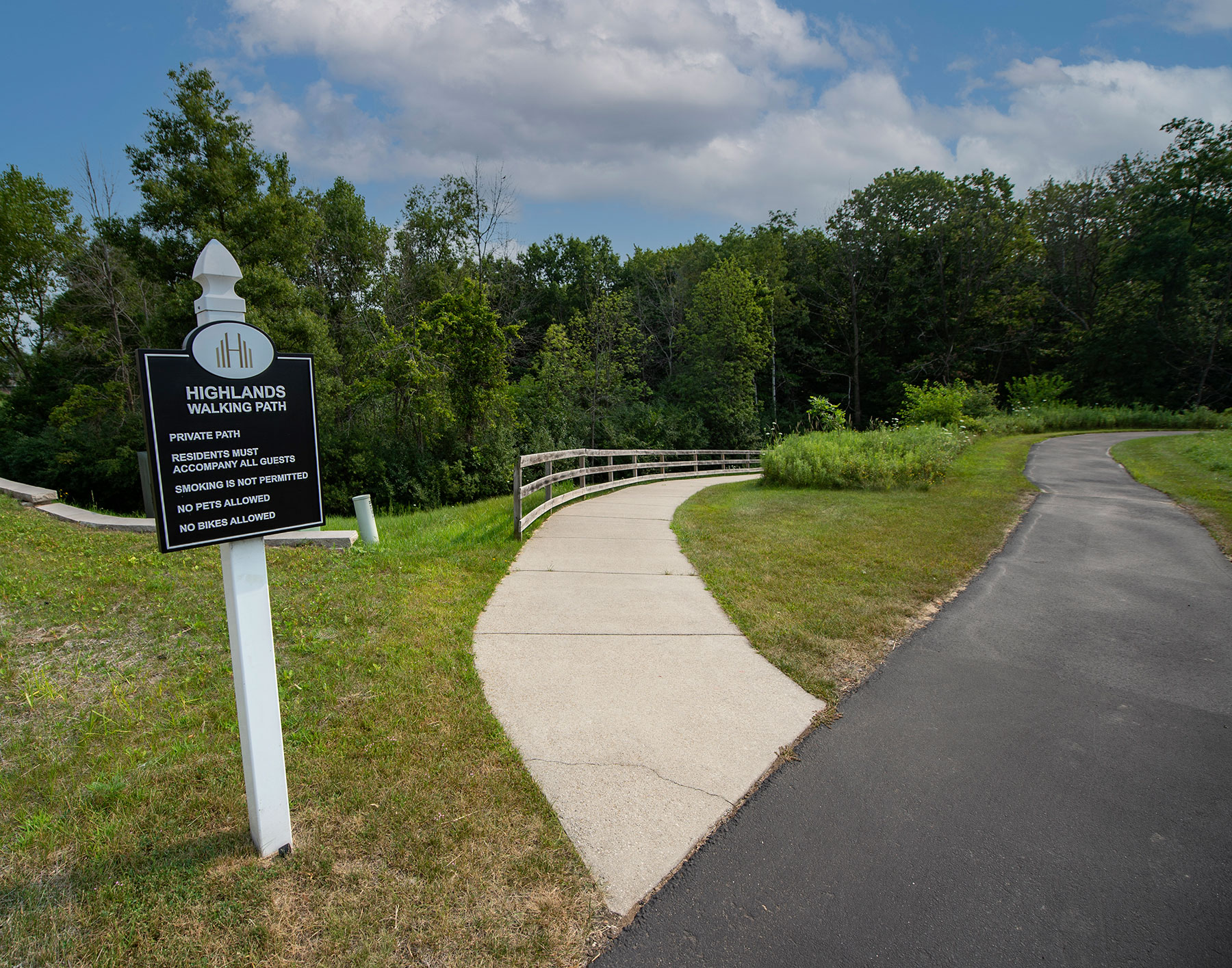 a path with a sign and a fence on the side of a road