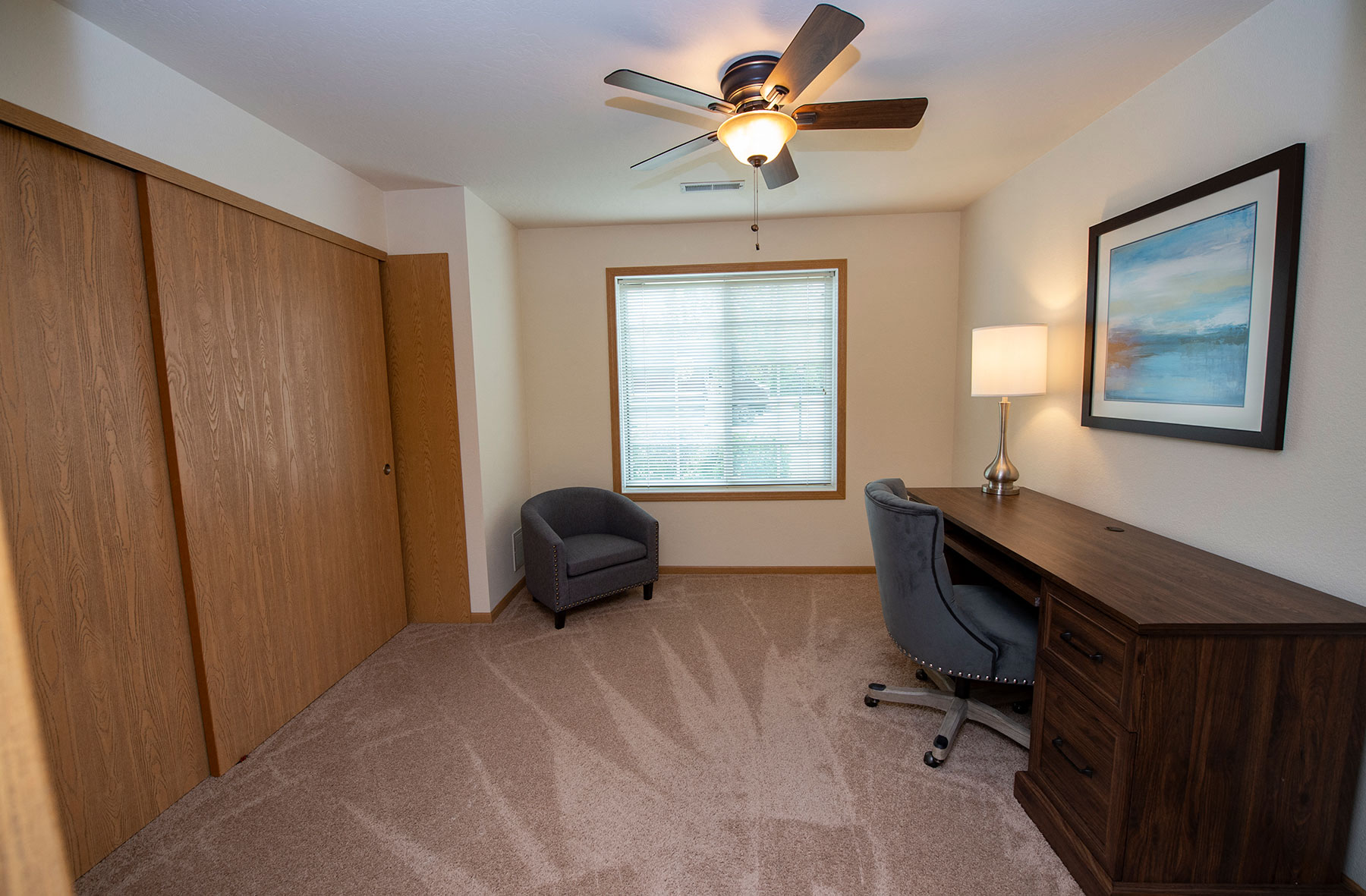 an office with a desk and a ceiling fan