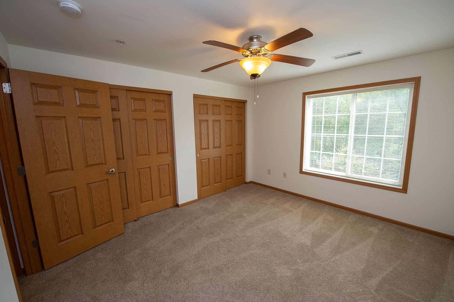 an empty bedroom with a ceiling fan and a window