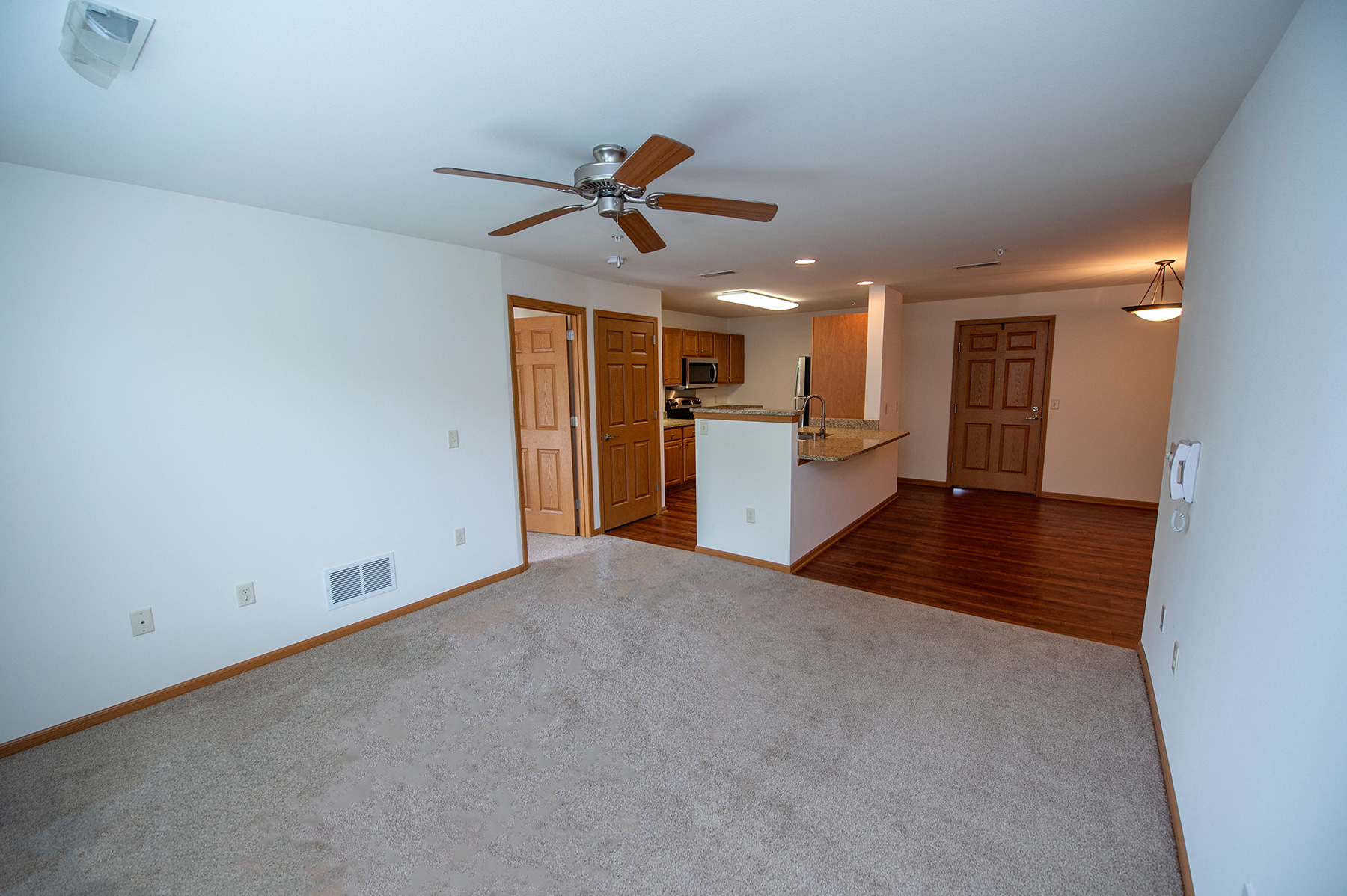 an empty living room and kitchen with a ceiling fan