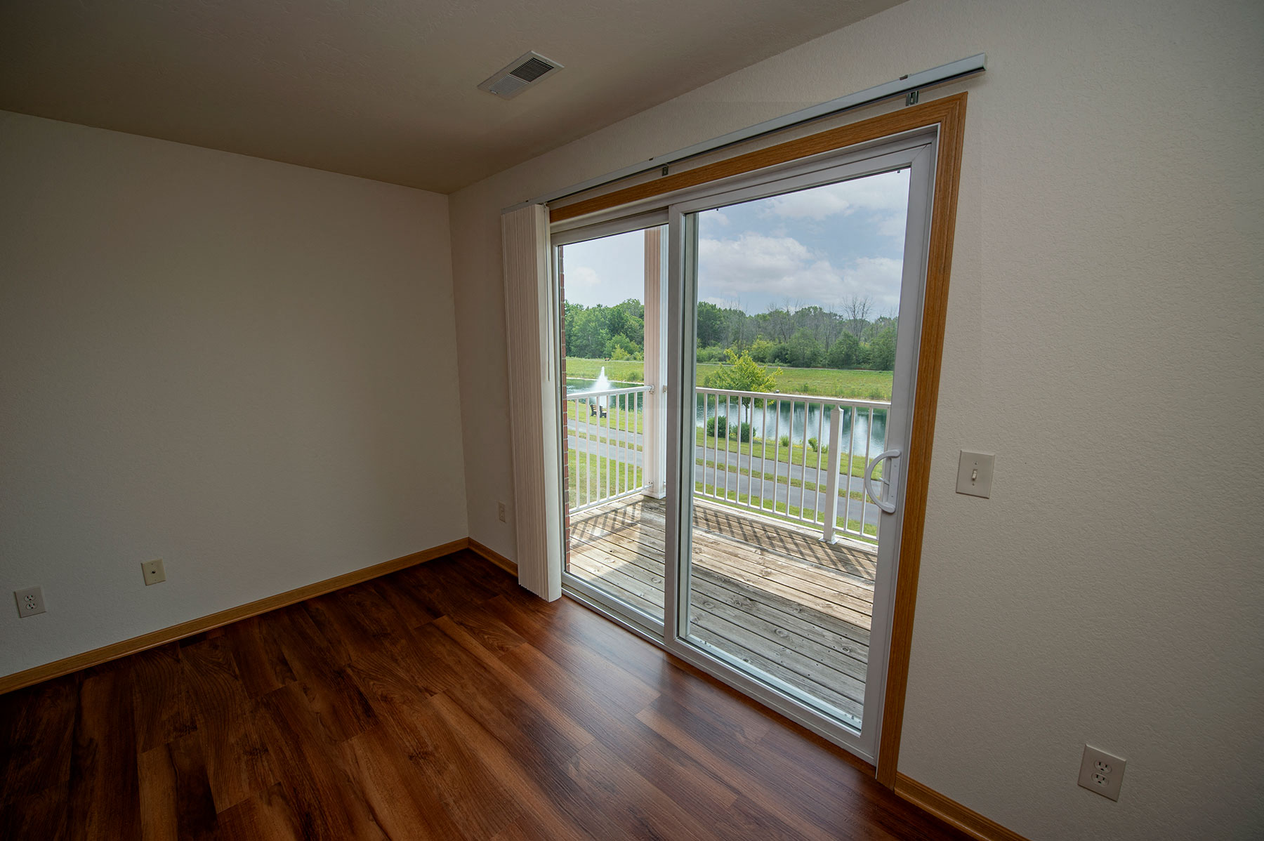 an empty living room with a sliding glass door to a balcony