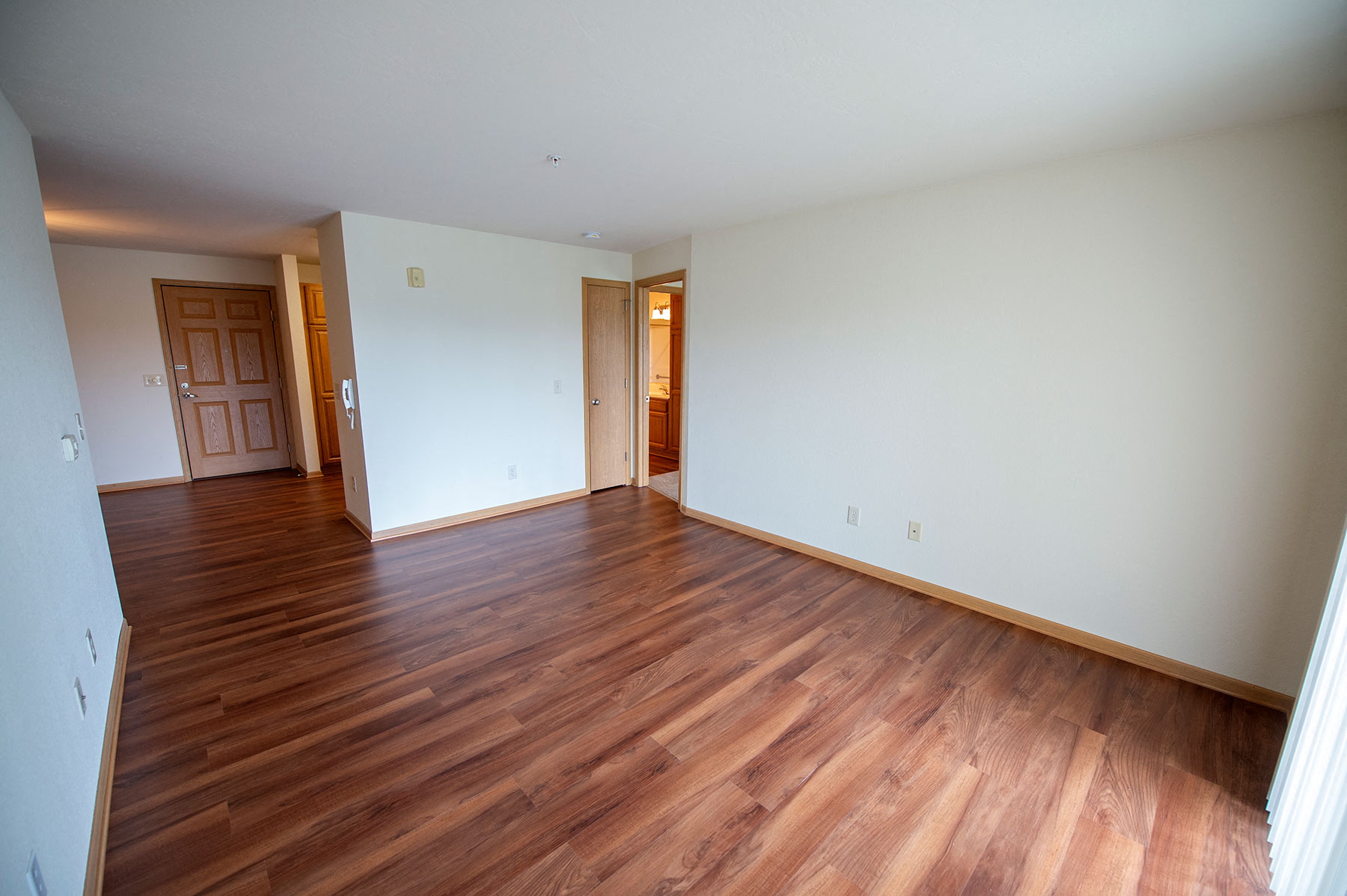 an empty living room with wooden floors and white walls