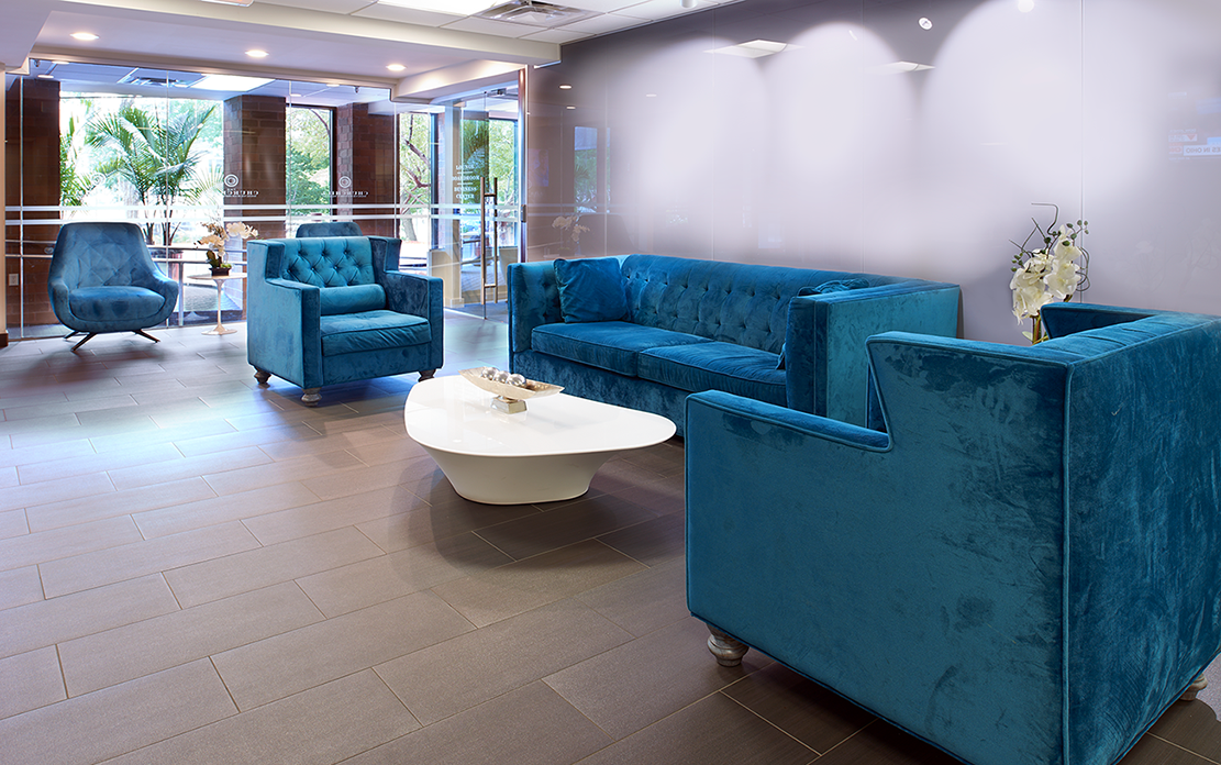 A living room with blue velvet furniture and a white coffee table.