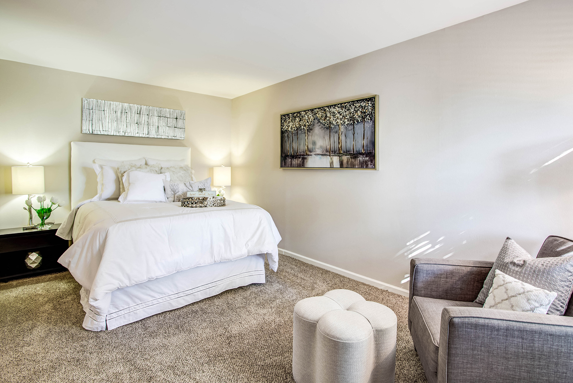 A bedroom with a large bed and a painting on the wall.