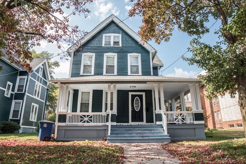 A blue house with a white porch and a black door.