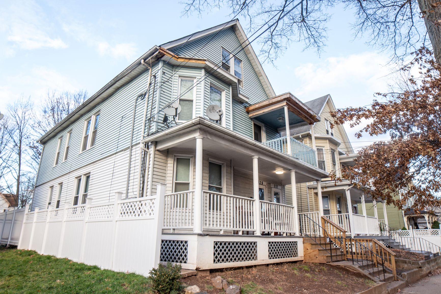 A two story house with a white fence in front.