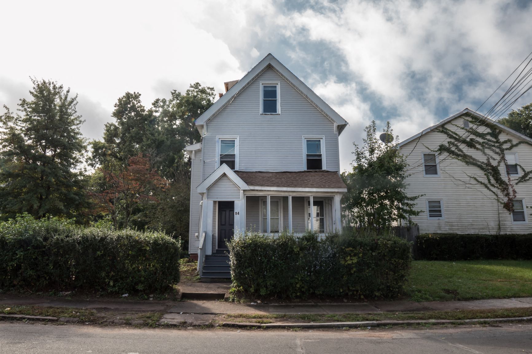 A white house with a grey roof and a small porch.