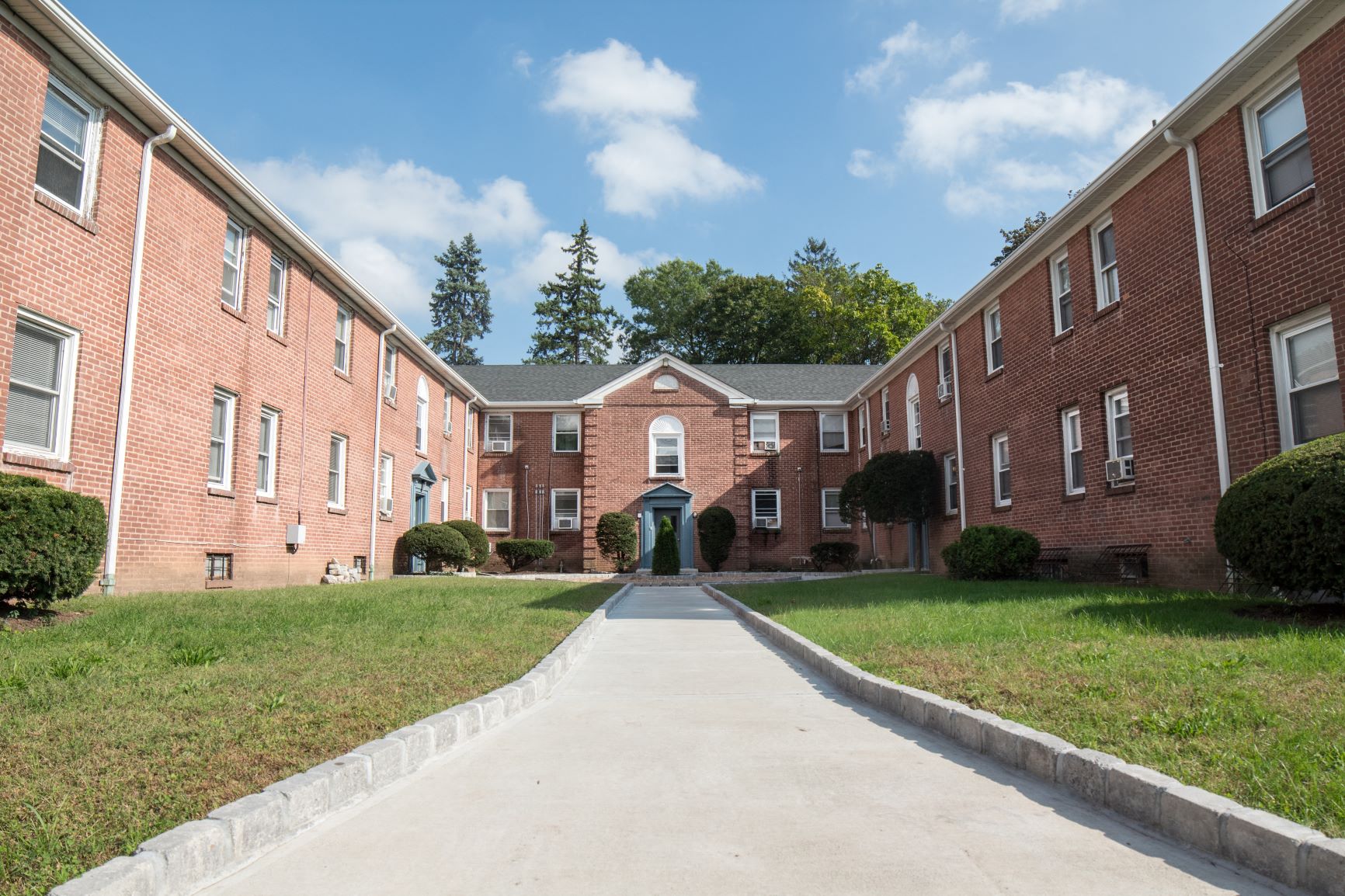 A long brick building with a green lawn in front.