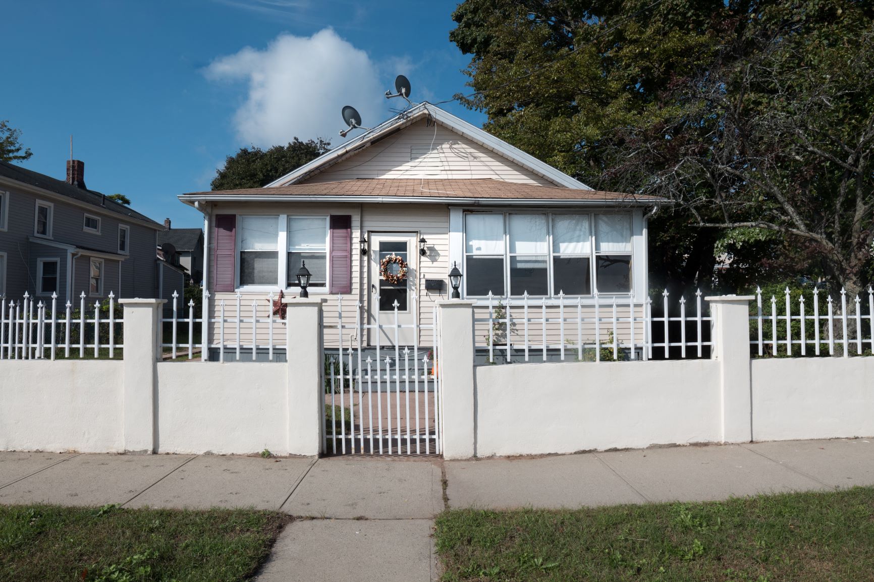 A white house with a red door and a white fence.