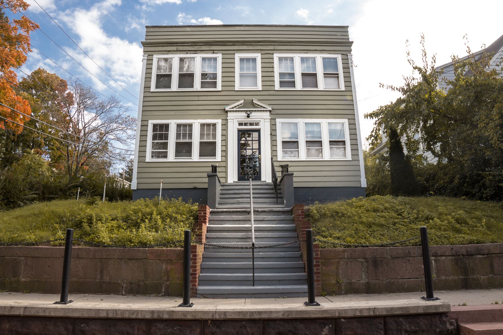 A grey building with a black door and steps leading up to it.