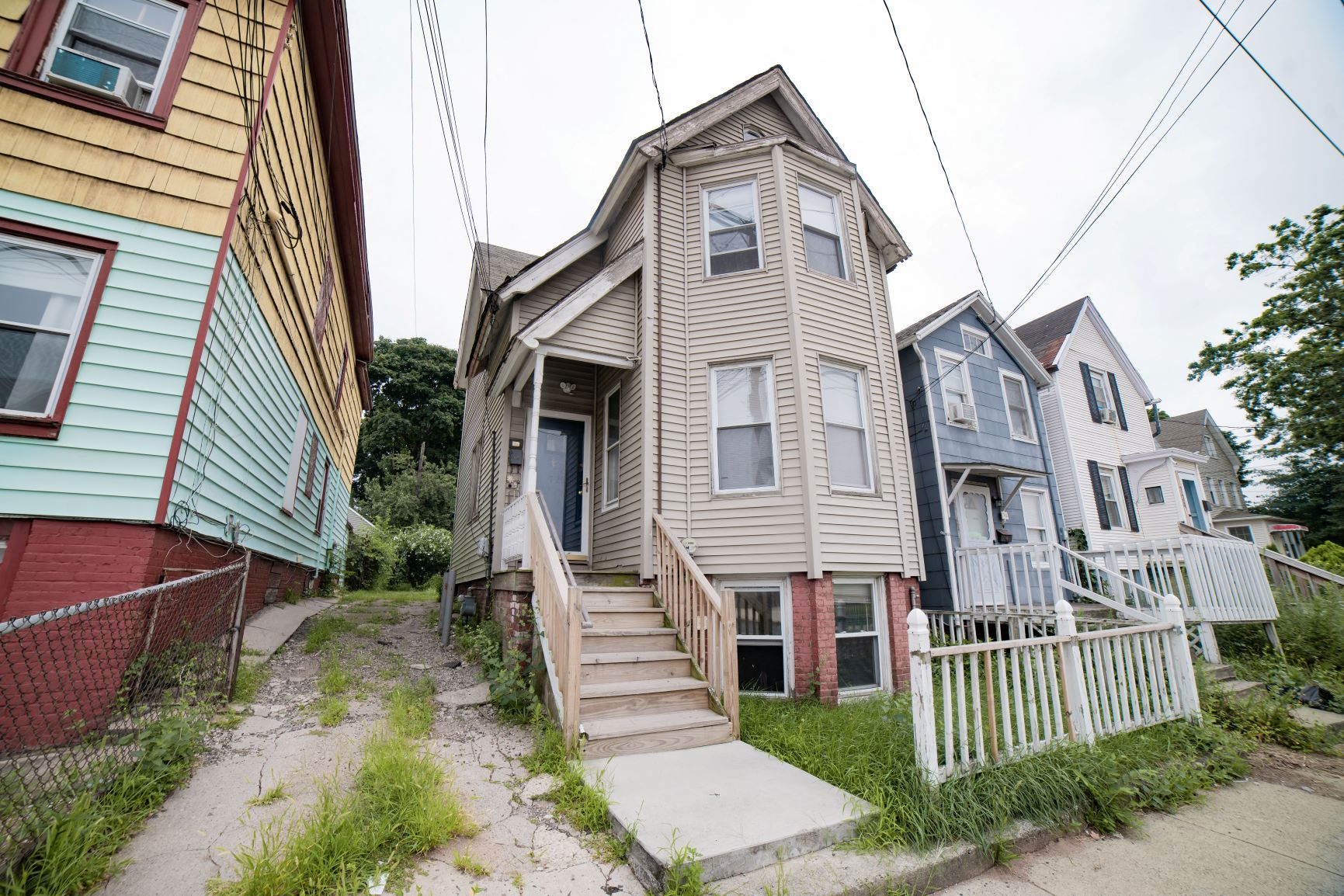 A yellow house is on the left and a grey house is in the middle of the picture.