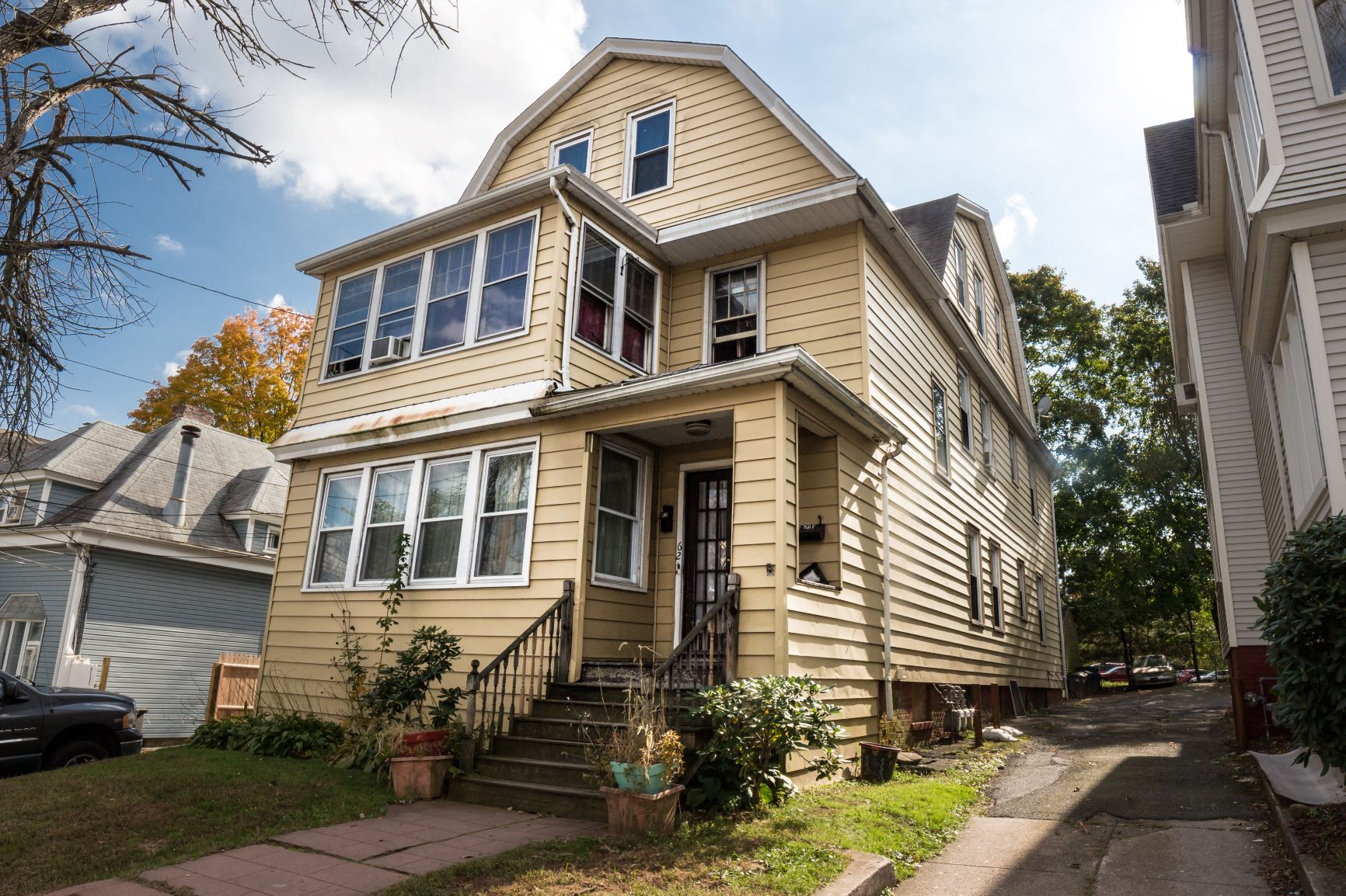 A two-story house with a front porch and a car parked in the driveway.