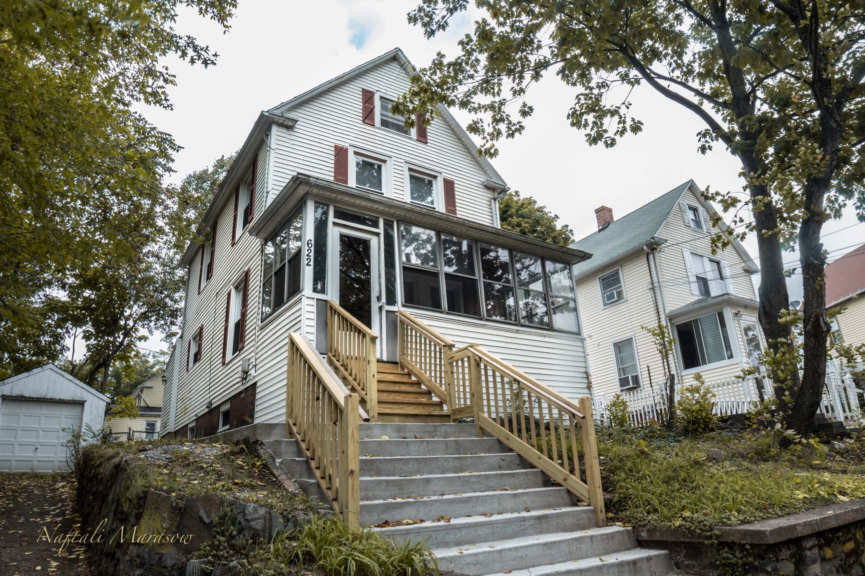 A white house with a red stripe on the roof and a balcony with a railing.