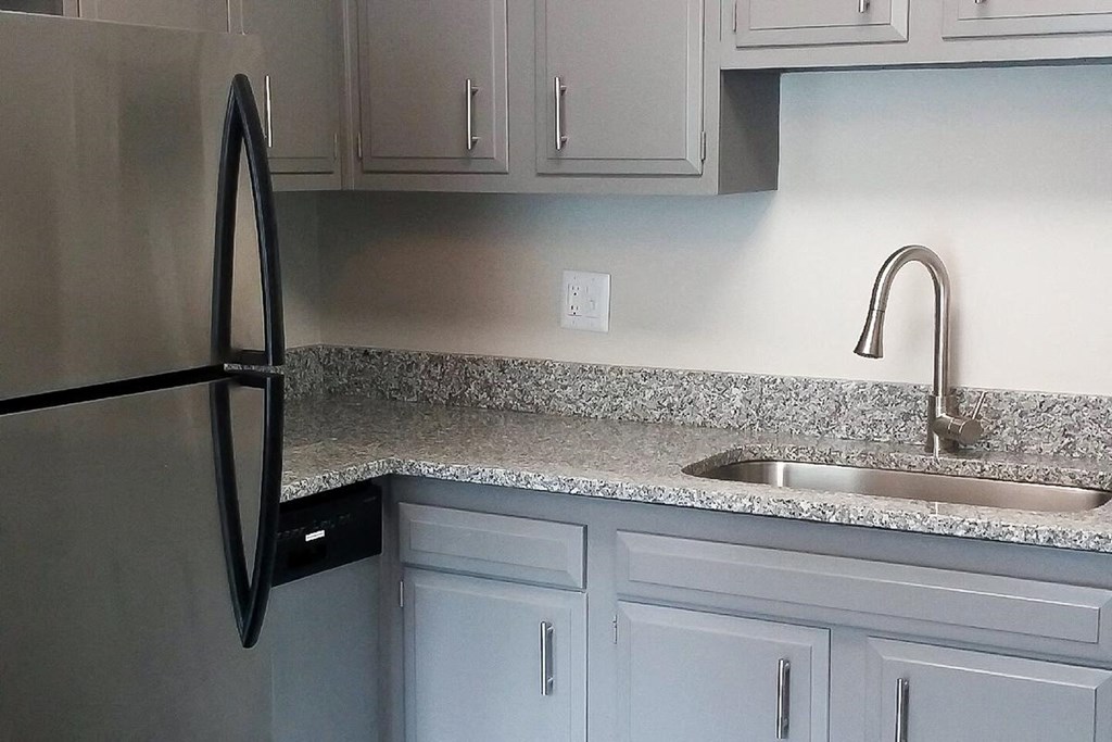 a kitchen with white cabinets and a sink and a refrigerator
