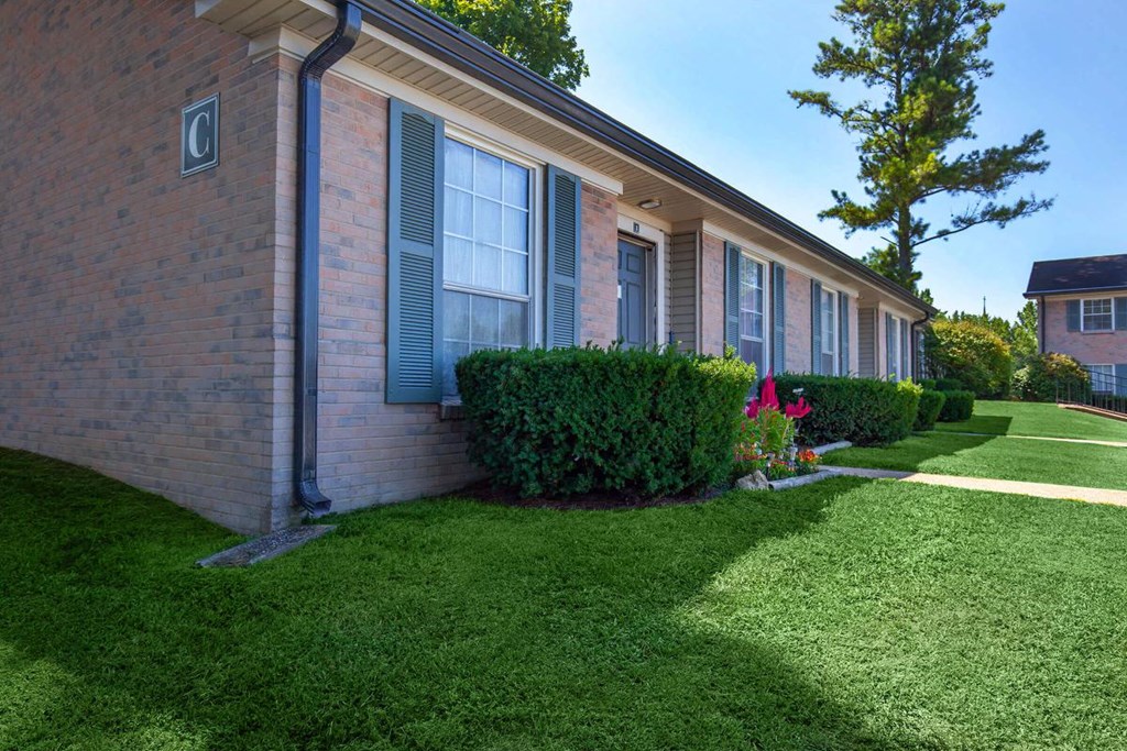 a side view of a brick building with green grass
