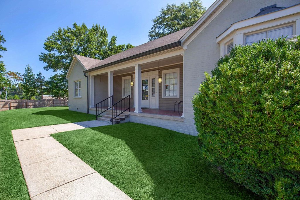 the front of a white house with a yard and grass