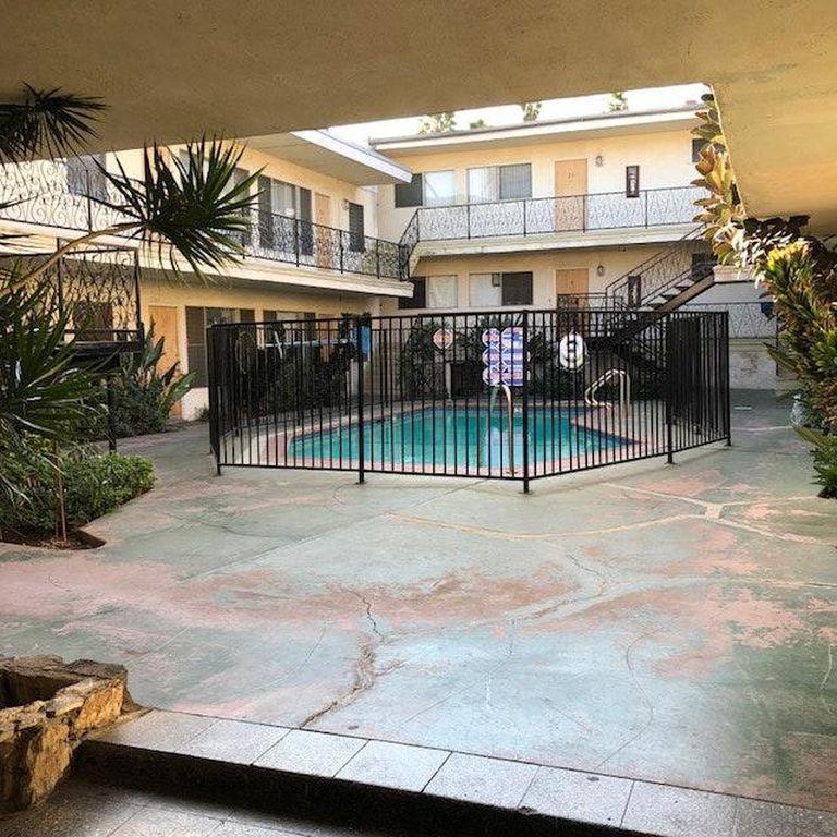 a small pool in front of a house with a black fence