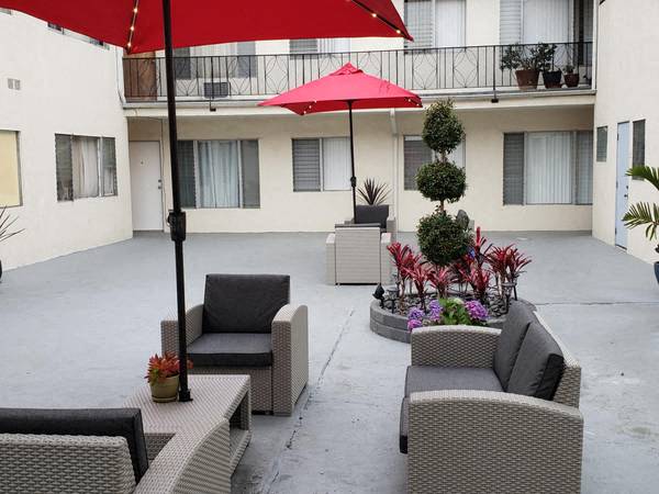 a patio with chairs and a red umbrella