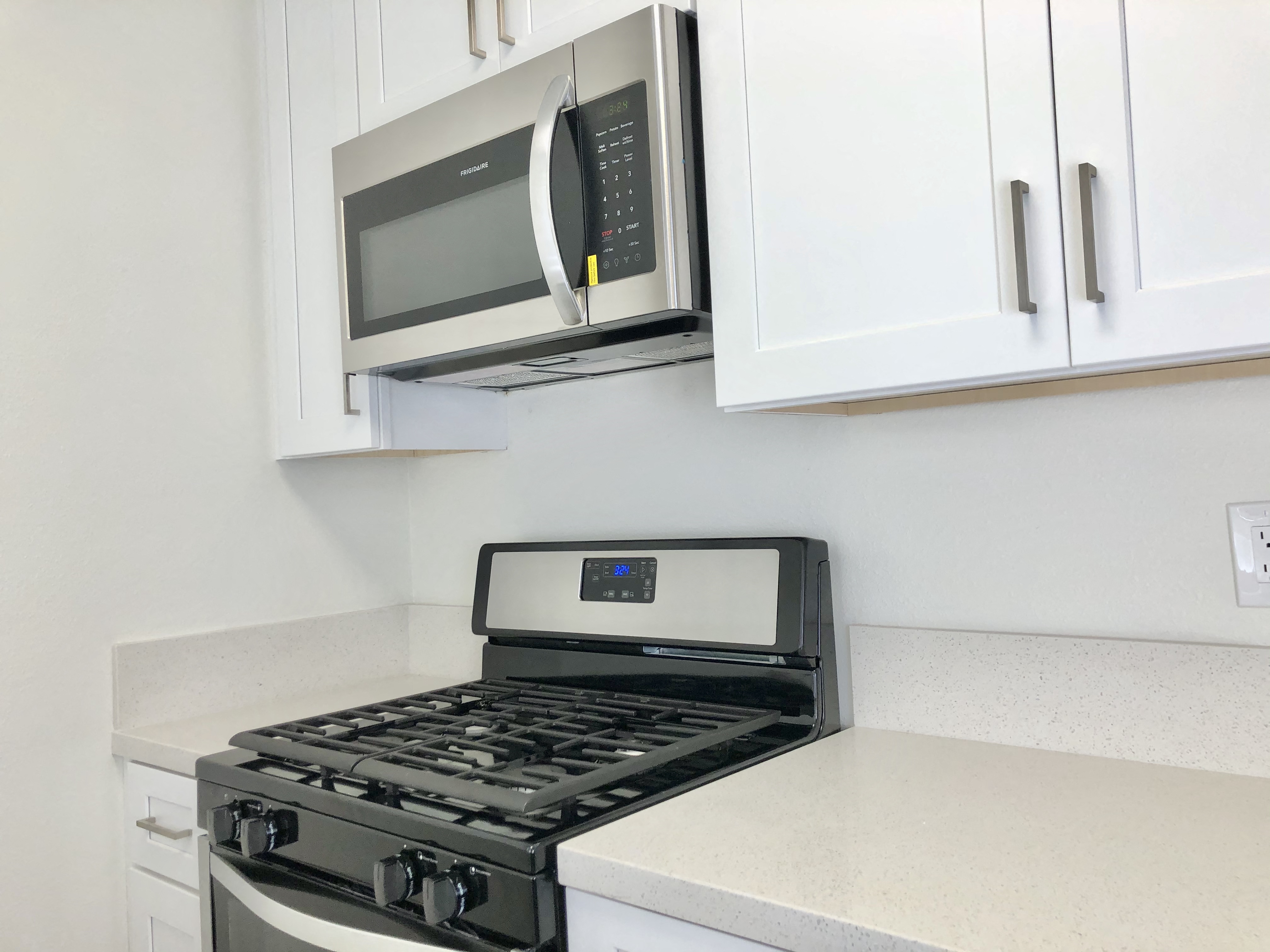 a kitchen with white cabinets and a stove and microwave