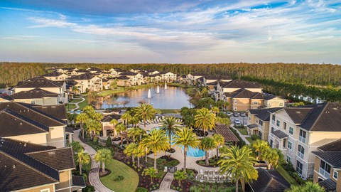 an aerial view of the resort with a lake and palm trees