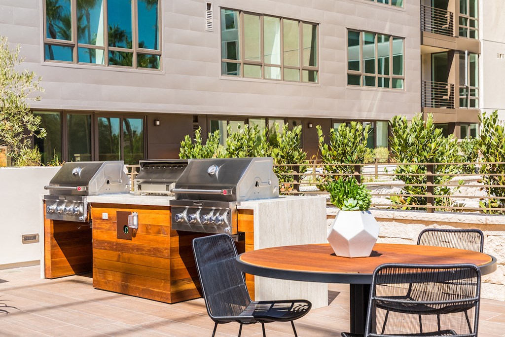 a patio with two barbecue grills and a table with chairs