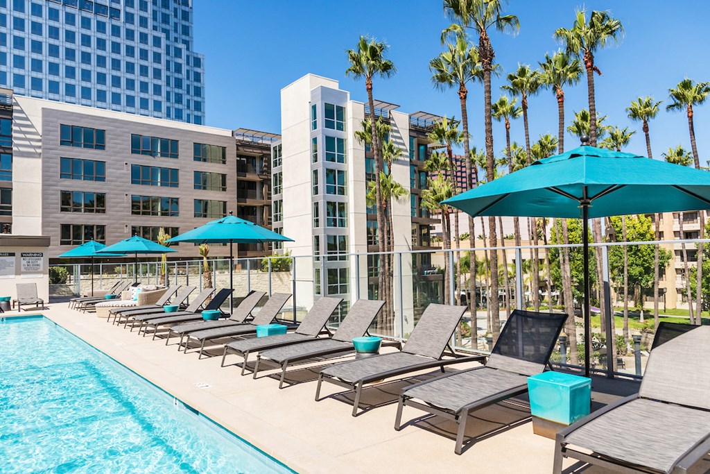 a pool with lounge chairs and umbrellas next to a building
