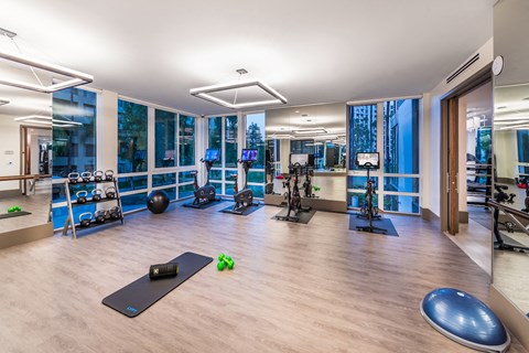 a gym with yoga equipment and windows with a view of the city