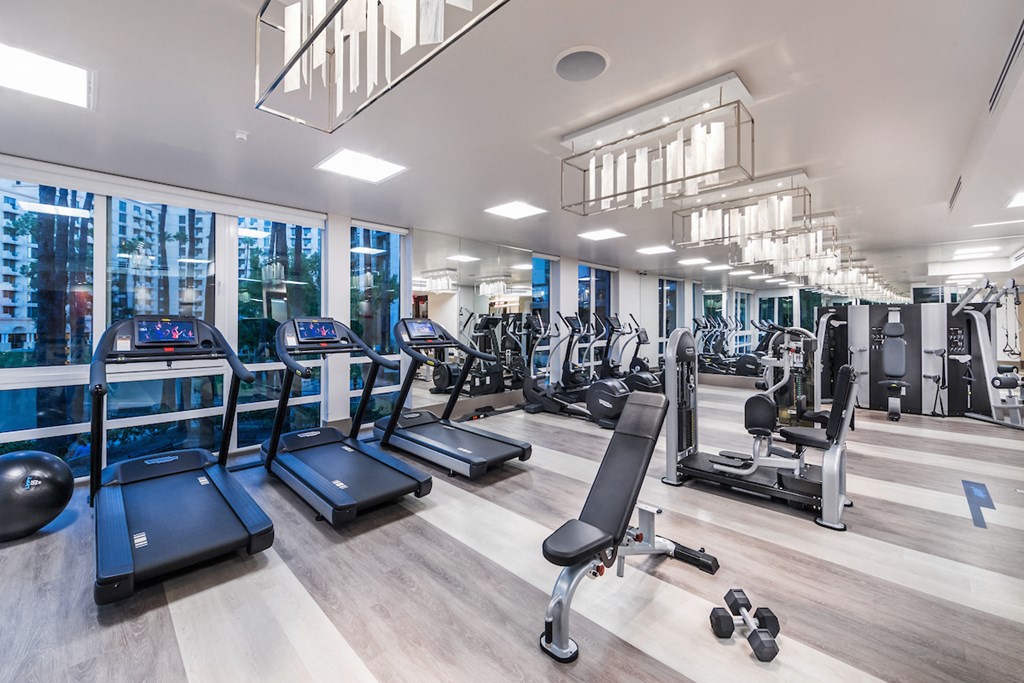 a gym with cardio equipment and glass walls