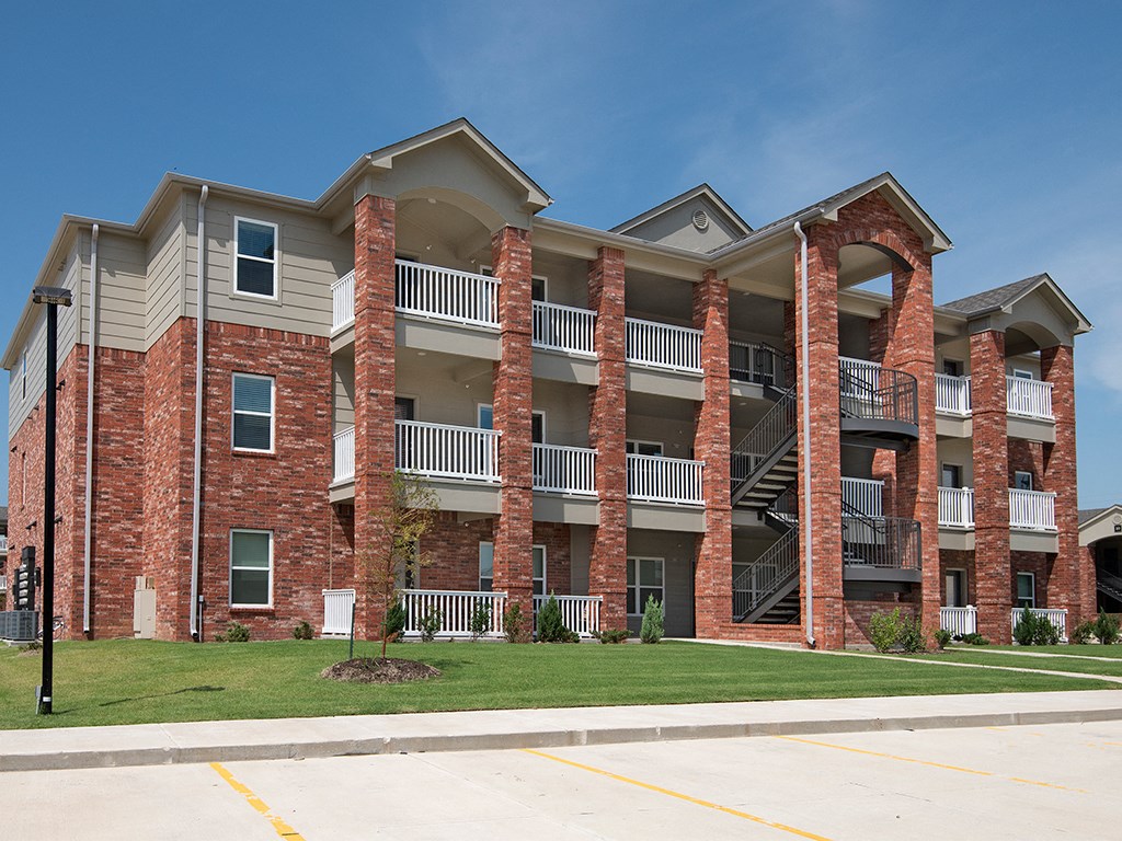 an apartment building with brick pillars and a lawn