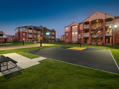 an outdoor basketball court at night at an apartment complex