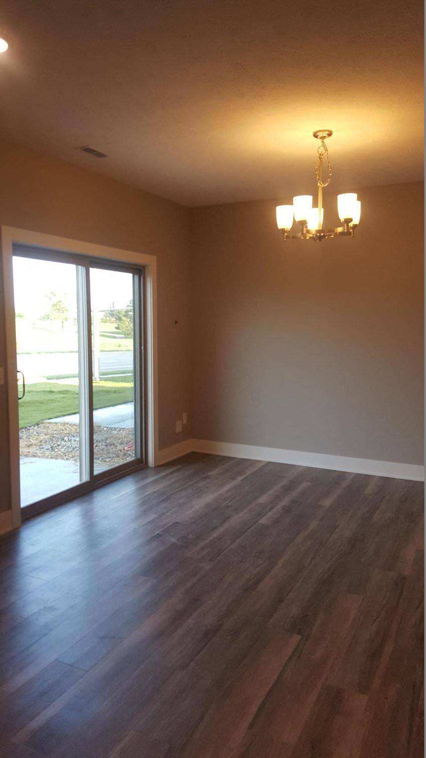 an empty living room with wood floors and a sliding glass door