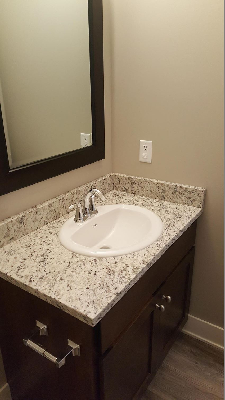 a bathroom sink with granite counter top and a mirror