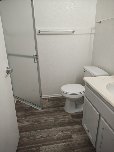 A white toilet sits in a bathroom next to a sink.