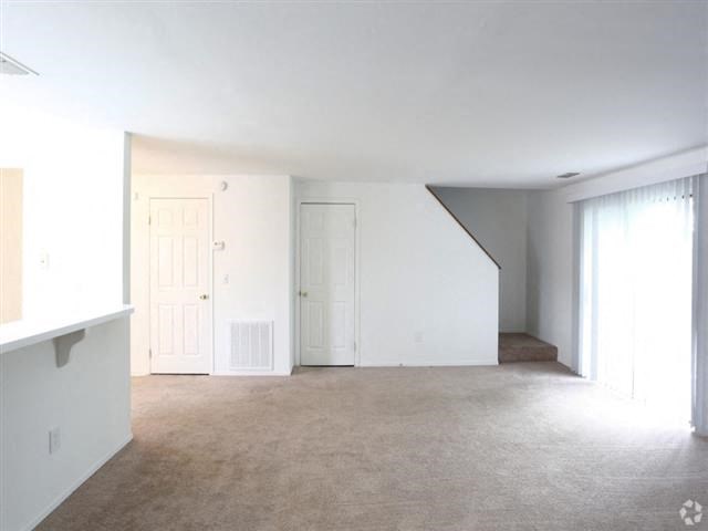 an empty living room with white walls and a white door