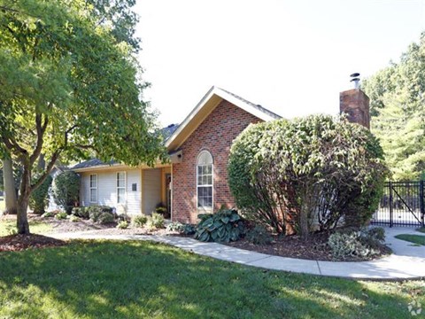a small brick house with a yard and a sidewalk