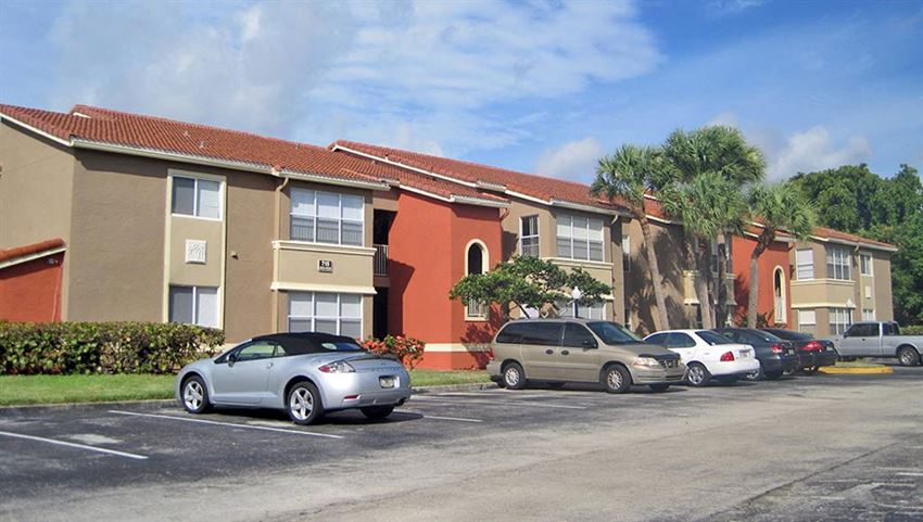 a parking lot with cars in front of an apartment building