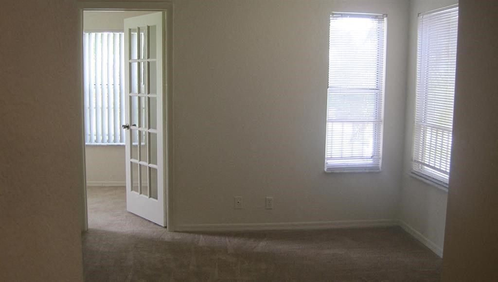 an empty room with an open door and two windows