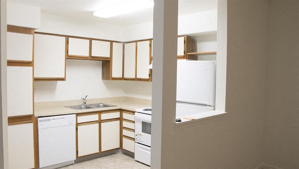 an empty kitchen with white appliances and wooden cabinets