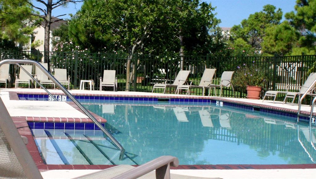 a swimming pool with chairs and trees in the background