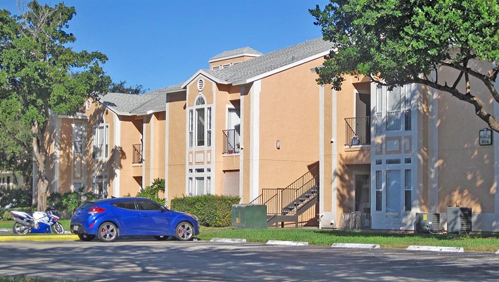 a blue car parked in front of an apartment building