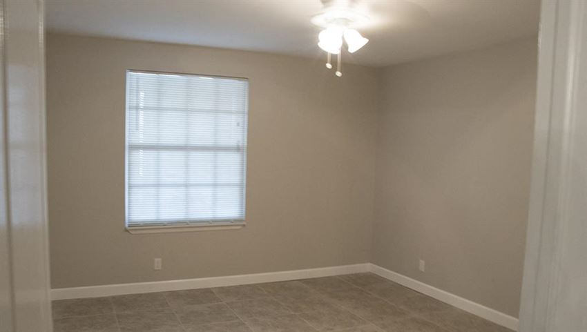 an empty room with a window and a ceiling fan