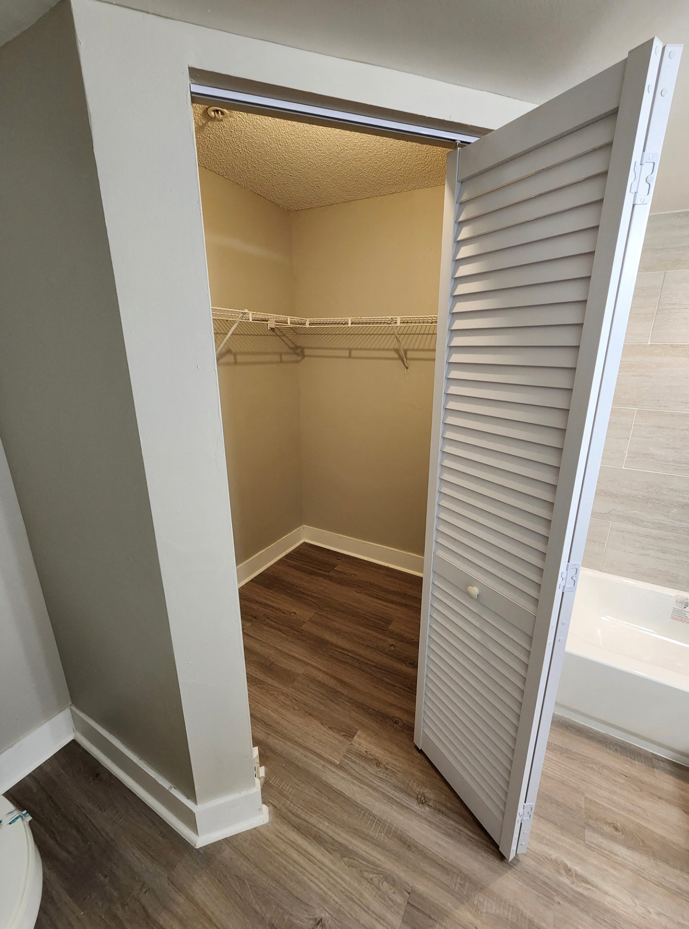 A white closet with a sliding door is open.