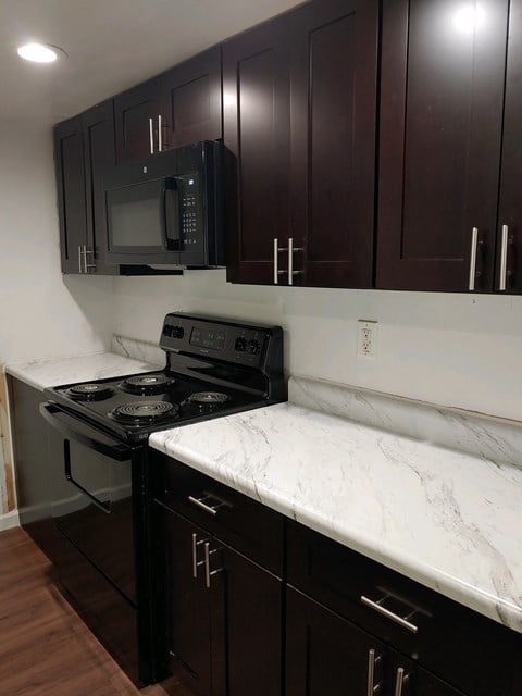 a kitchen with black and white marble counter tops and a stove and microwave